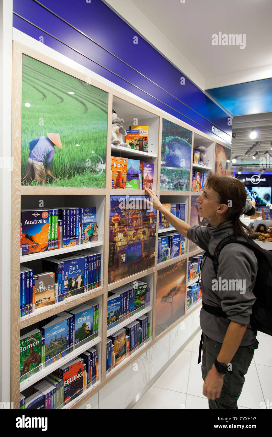 Backpacker à Lonely Planet guide books dans le Lonely Planet shop à l'aéroport de Manchester, Manchester, Royaume-Uni. Banque D'Images