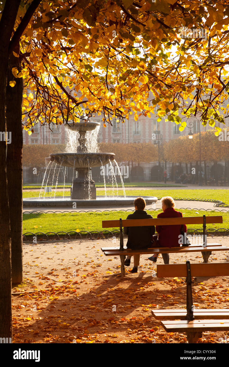Deux amis appréciant un matin d'automne à la Place des Vosges, le quartier du Marais, Paris, Ile-de-France France Banque D'Images
