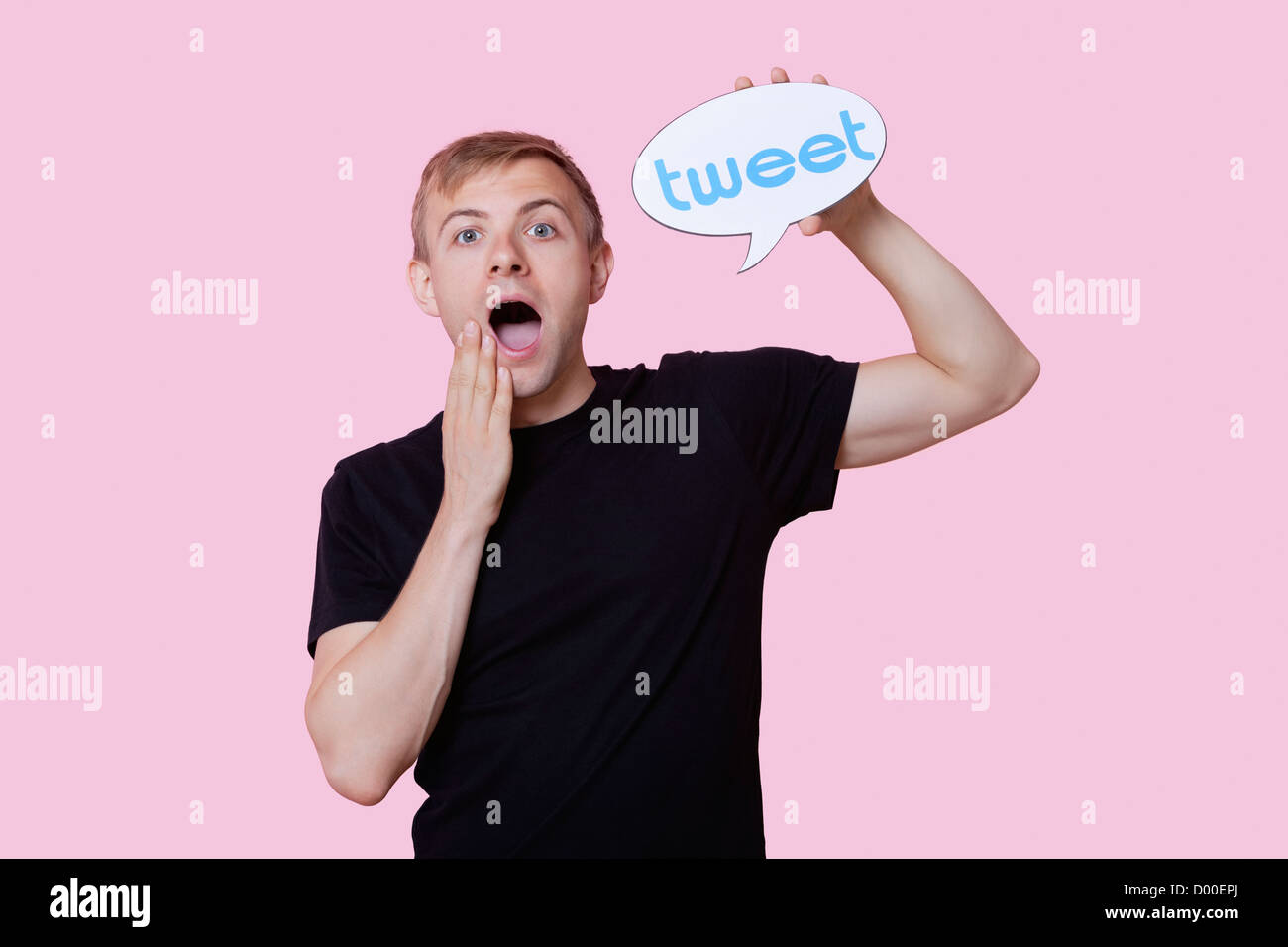 Portrait of young man holding surpris tweet bubble contre fond rose Banque D'Images