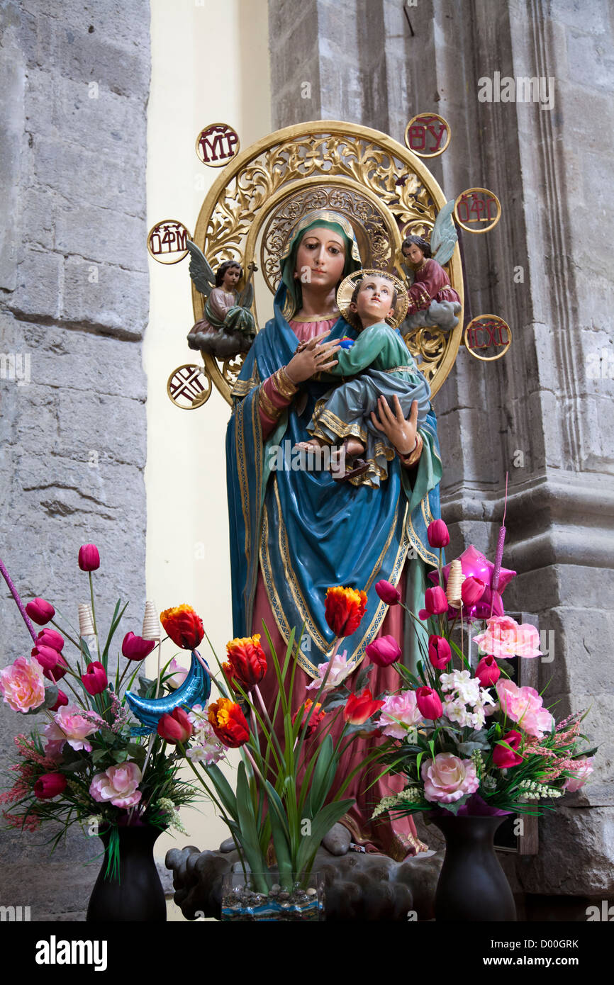 Vierge Marie portant l'Enfant Jésus Statue et fleurs Banque D'Images