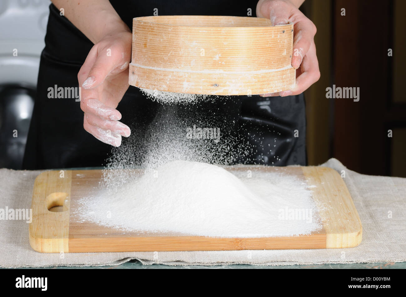Tamiser la farine à travers un tamis pour une plaque à pâtisserie