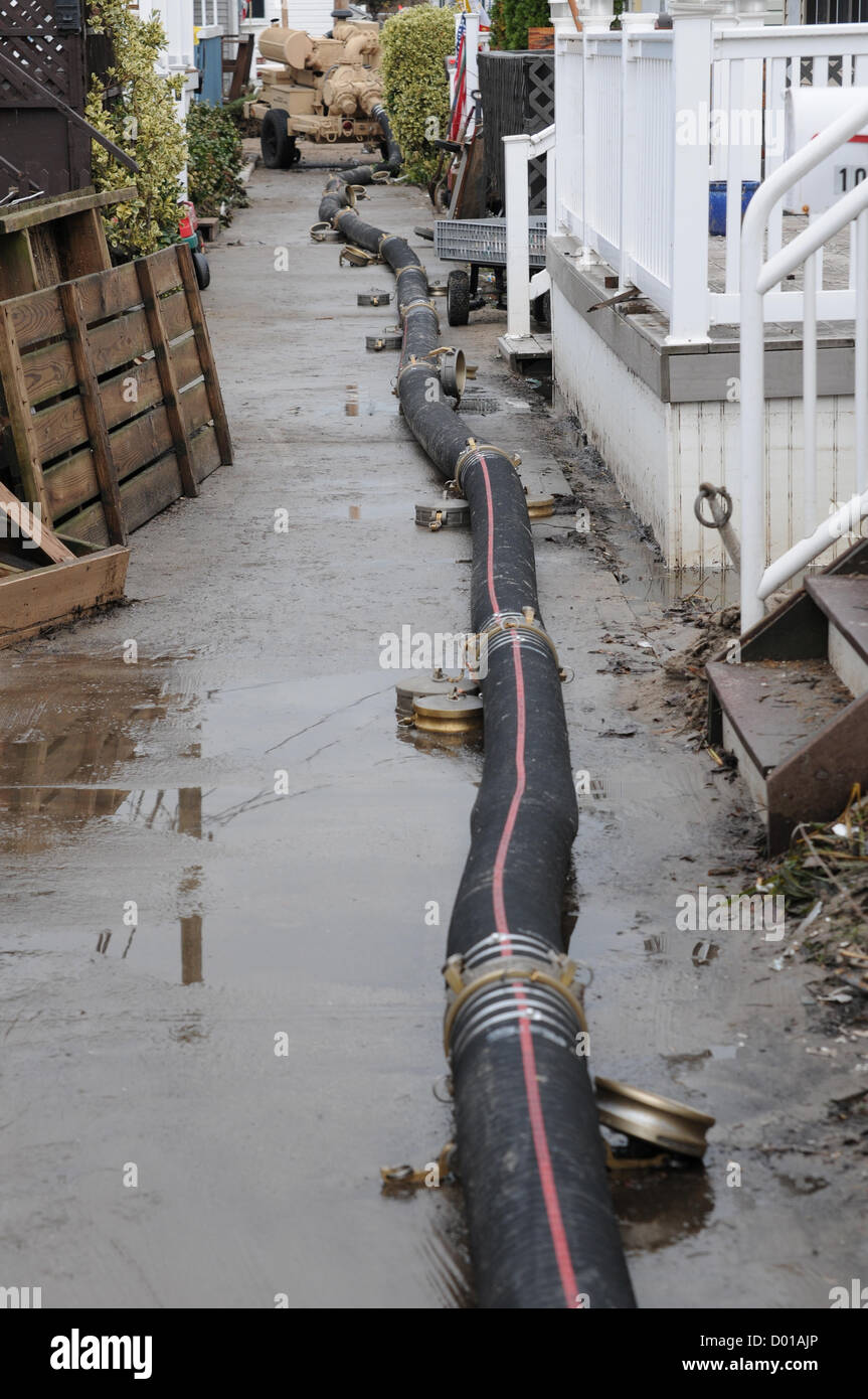 L'eau de tempête de l'Ouragan Sandy s'écoule à travers six pouce étiré flexibles le long d'une côte à pied le 13 novembre lors d'une zone résidentielle de Breezy Point, N.Y. Malgré un travail dans des conditions météorologiques difficiles, la 401st Détachement Quartier-maître, Lock Haven, Pennsylvanie, utilise de grandes pompes, capables de pomper 600 gallons par minute, pour enlever l'eau des zones les plus touchés par l'Ouragan Sandy. Une fois que l'eau est enlevée, les travaux nécessaires vont commencer à rétablir les services publics pour le complexe. L'unité est l'appui de l'Agence fédérale de gestion des urgences, de l'état, les collectivités locales et les représentants de la ville. Banque D'Images