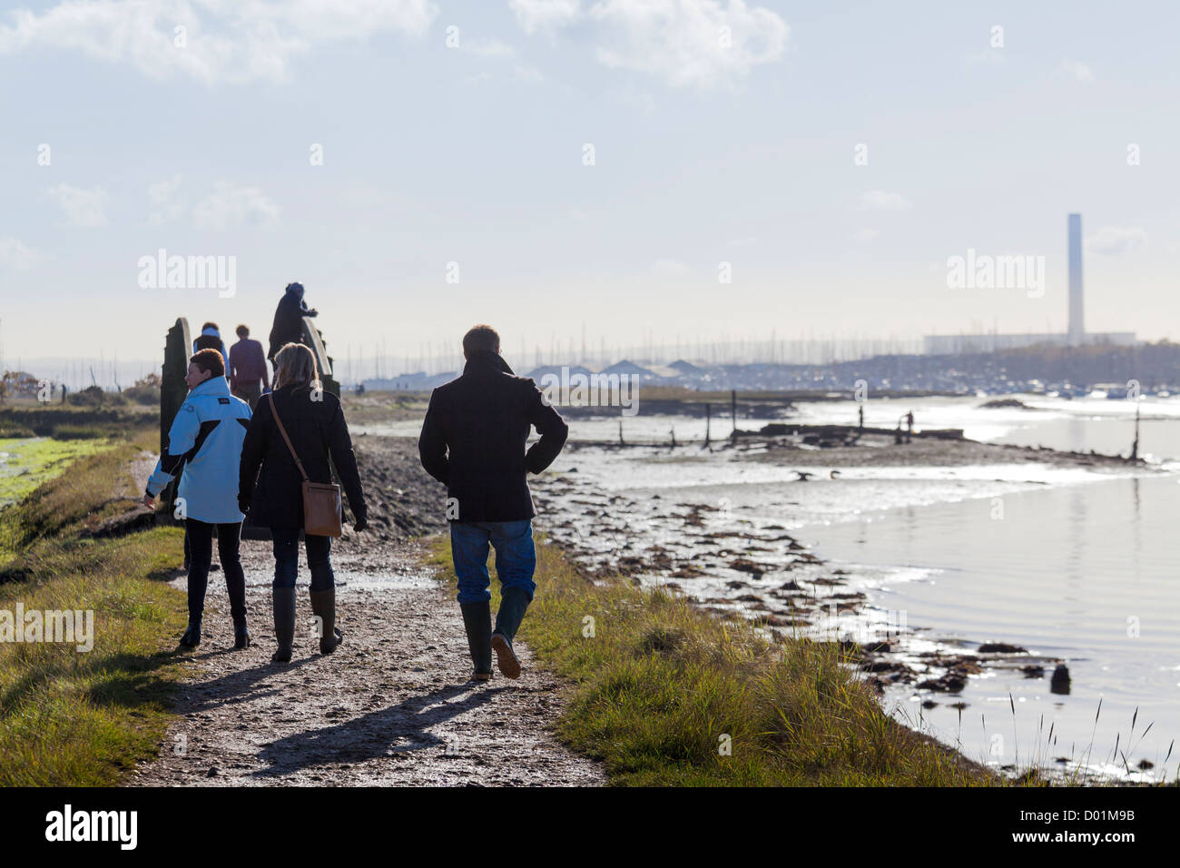 Promeneurs sur le sentier le long de l'estuaire de la rivière Hamble avec la tour de Faqwley power station dans la distance Banque D'Images