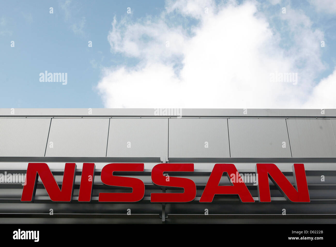 La voiture Nissan logo de l'entreprise chez un concessionnaire avec ciel bleu derrière elle. Banque D'Images
