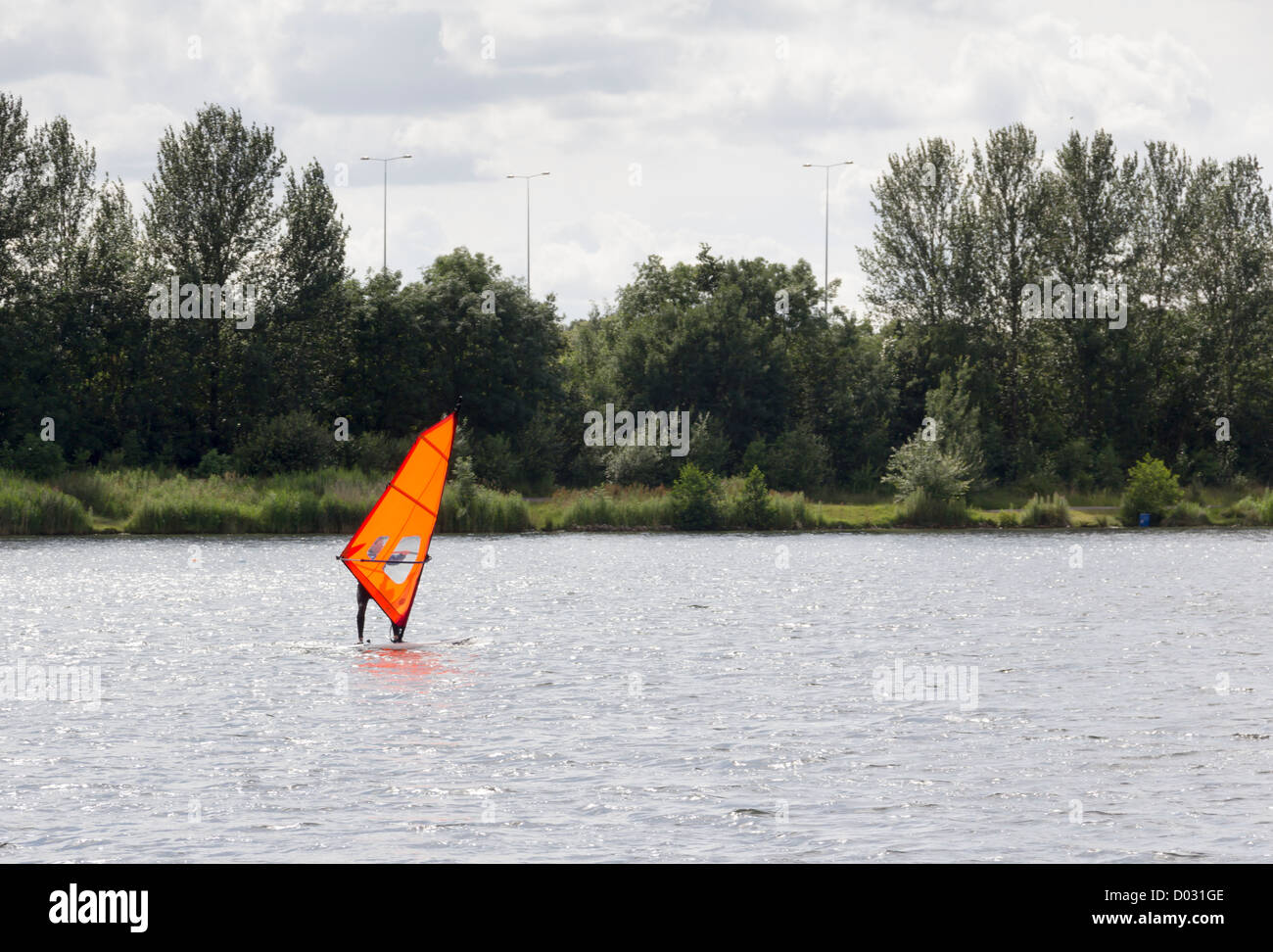 Windsurfer avec orange planche à voile en vente Water Park, près de Manchester. Le Parc de l'eau fournit également des installations de gestion des inondations. Banque D'Images
