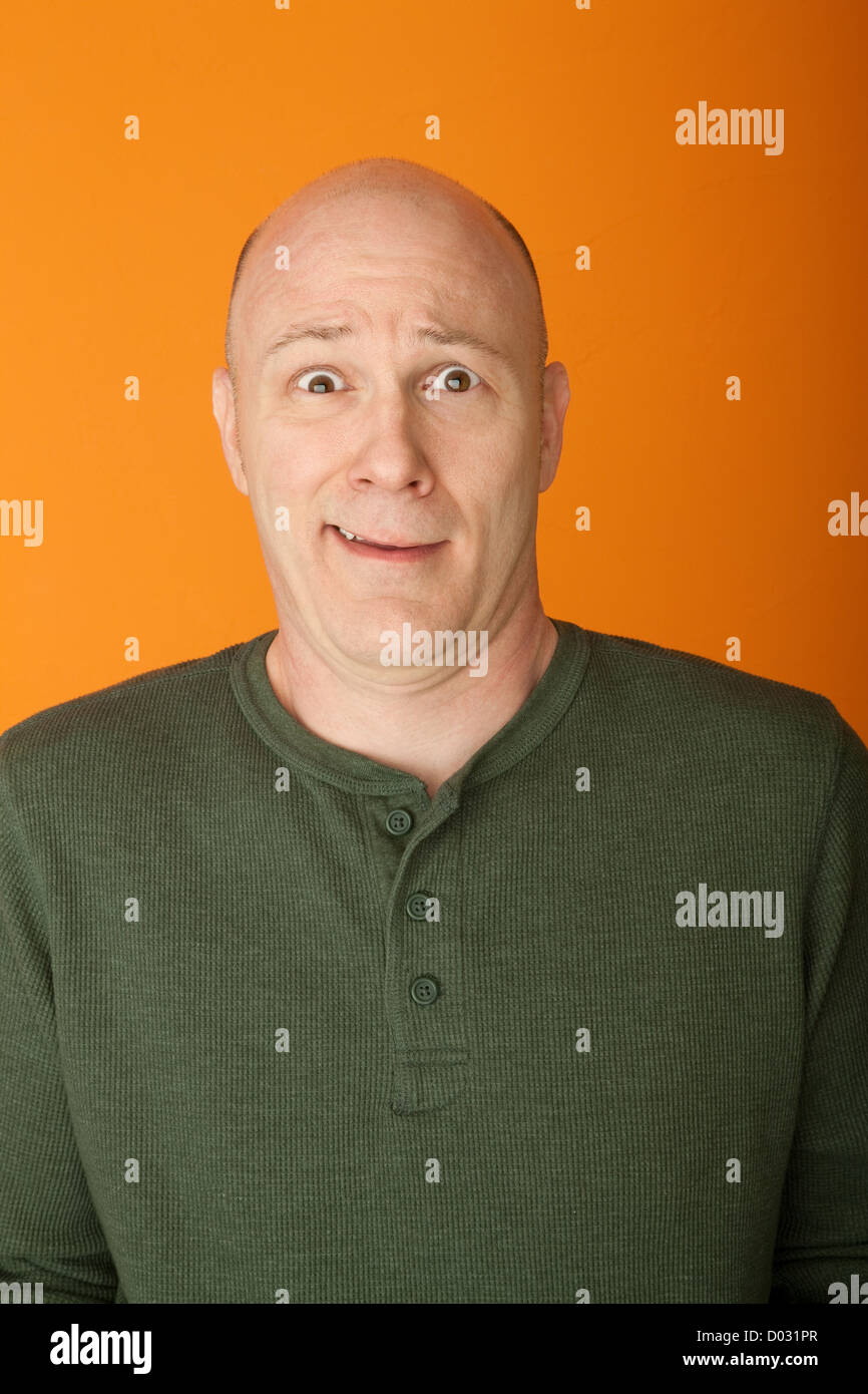 Perplexe bald middle-aged man sur fond orange Banque D'Images