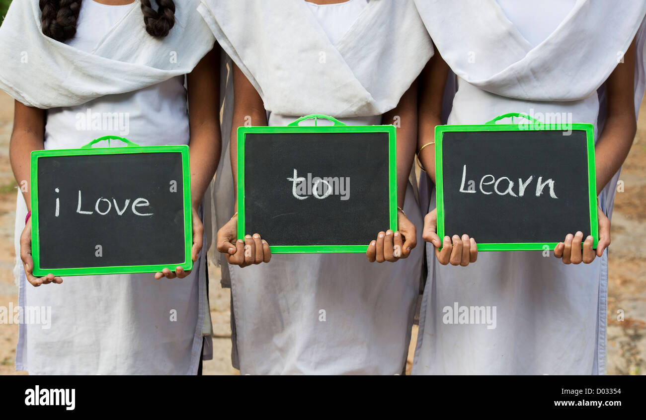 Trois filles de l'école de village indien avec J'aime apprendre écrit sur un tableau. L'Andhra Pradesh, Inde Banque D'Images