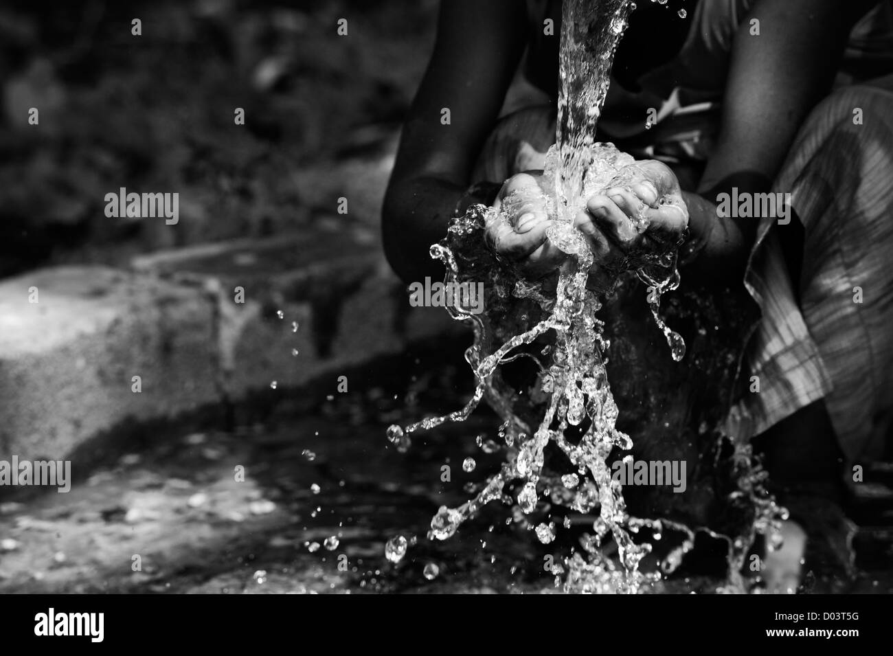 L'eau d'une pompe manuelle dans un village de l'Inde rurale et verser dans un indien pour les mains. L'Andhra Pradesh, Inde. Monochrome Banque D'Images