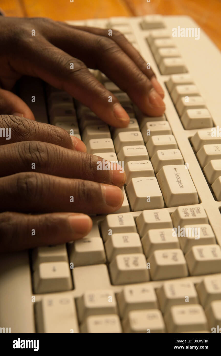 African man's hands typing on computer keyboard gris Banque D'Images