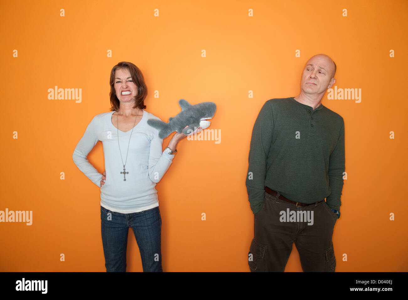 Belle femme de race blanche menace mari avec jouet requin Banque D'Images