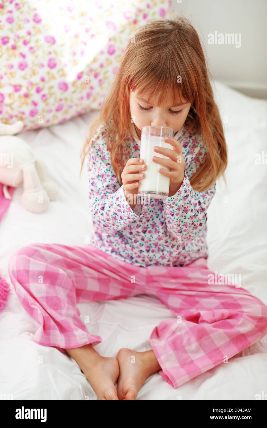 Accueil de l'enfant de boire du lait au lit Banque D'Images