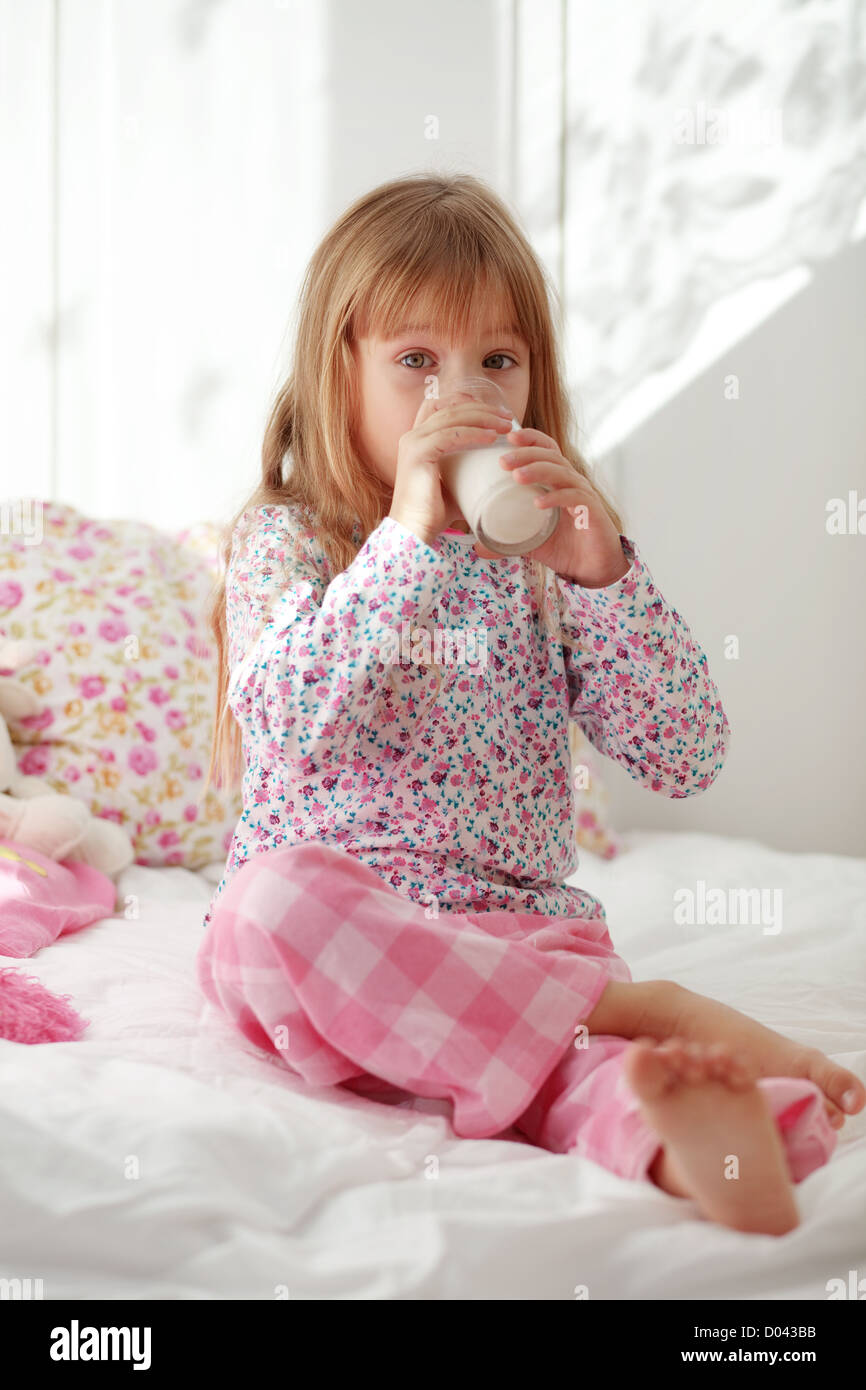 Accueil de l'enfant de boire du lait au lit Banque D'Images
