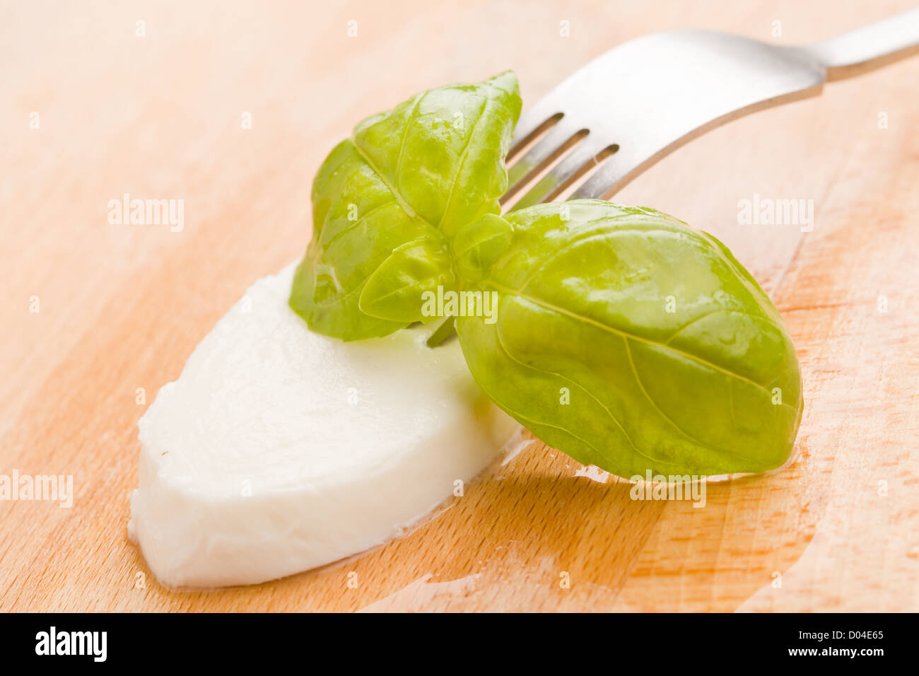 Photo de délicieux mozzarella juteuse avec feuille de basilic sur planche à découper en bois Banque D'Images