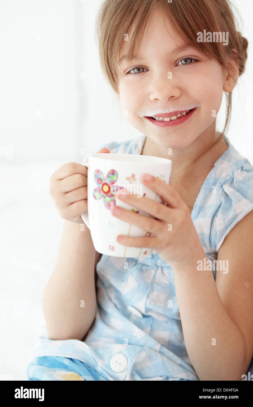 Accueil de l'enfant de boire du lait au lit Banque D'Images