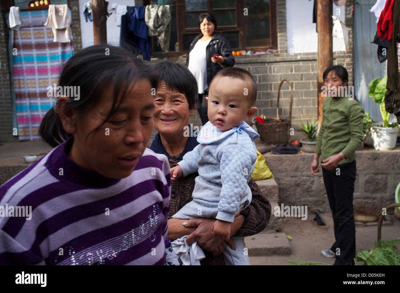 Une dame d'un aîné est titulaire d'un petit garçon à une cour dans Laofen, village du comté de Pingshan, Hebei, Chine. 23-Oct-2012 Banque D'Images