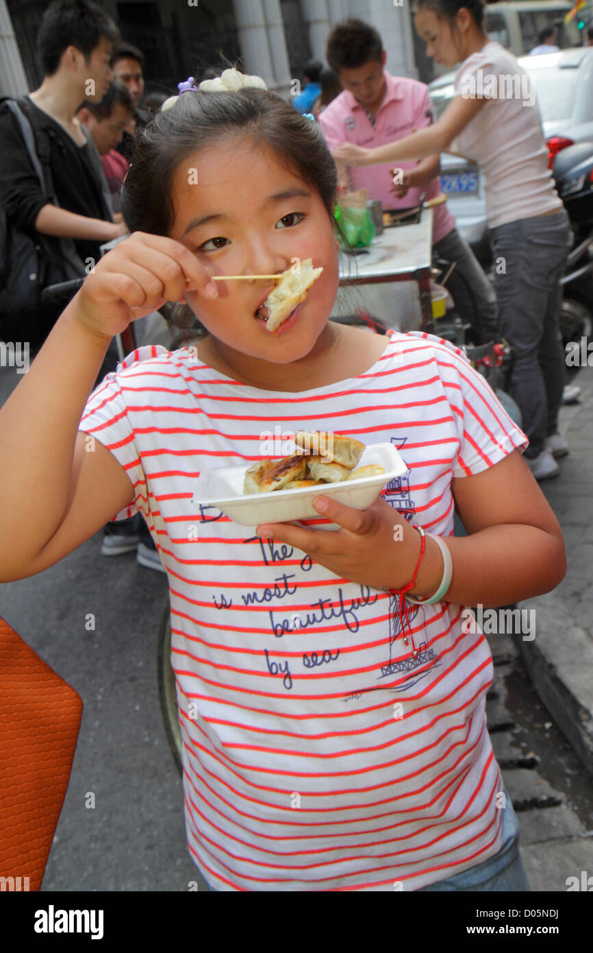 Shanghai Chine, quartier chinois de Huangpu, Dianchi Road, Asian girl girls, jeune, femmes enfants, enfants, boulettes, manger, nourriture, rue, vendeurs stall Banque D'Images