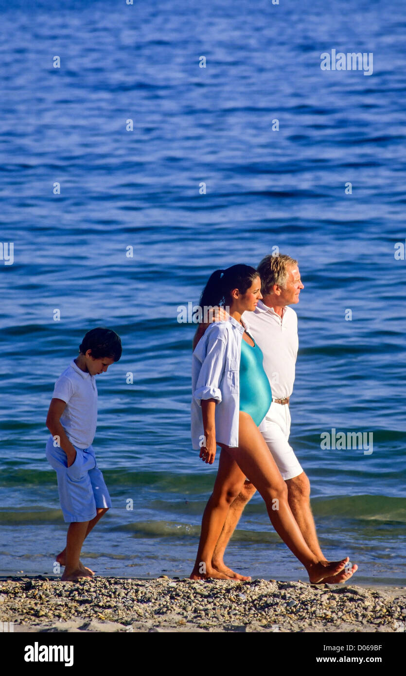 Sulky garçon marchant derrière couple avec femme enceinte sur mer Banque D'Images