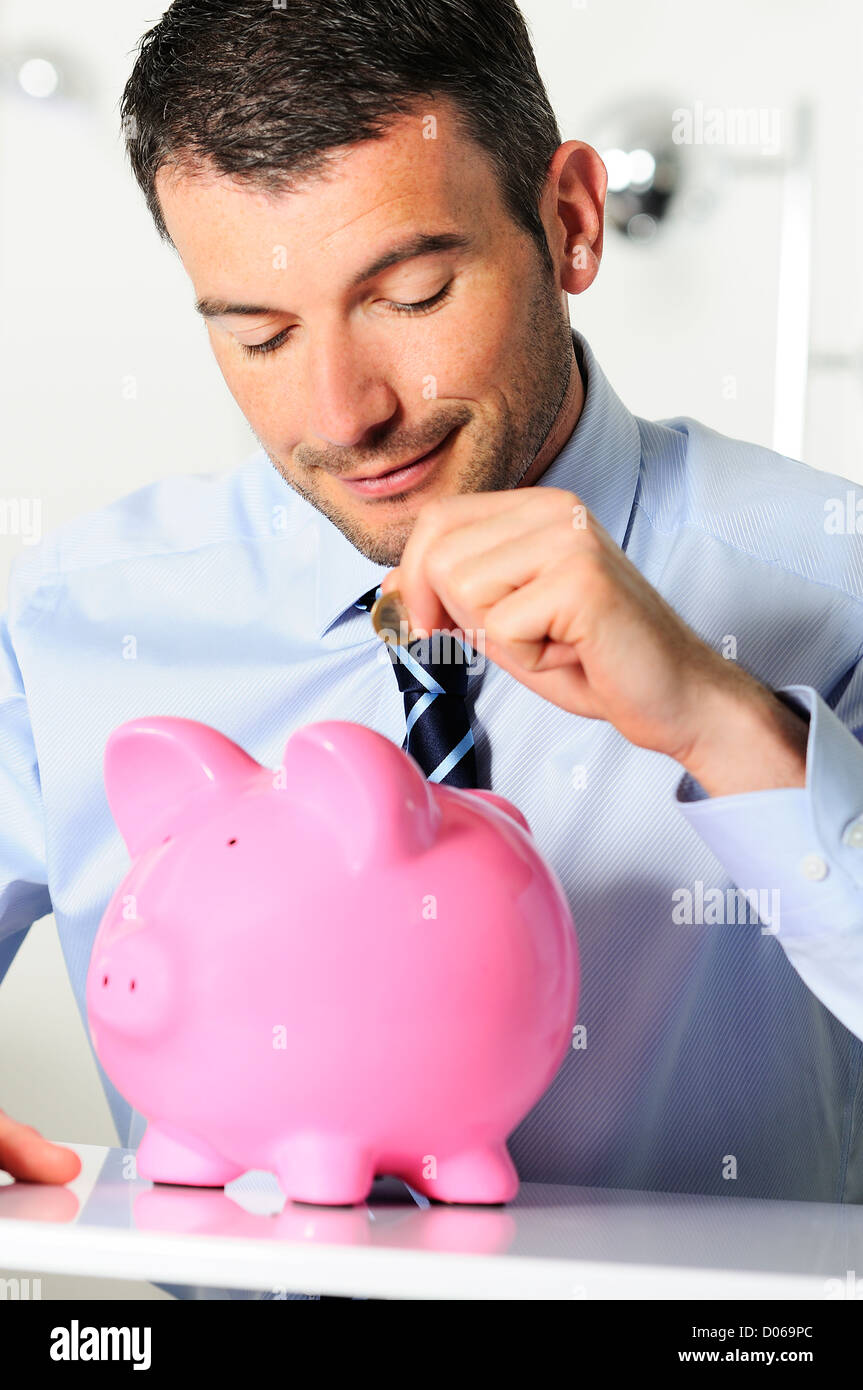 Tapis d'homme d'une pièce dans la tirelire en forme de cochon rose Banque D'Images