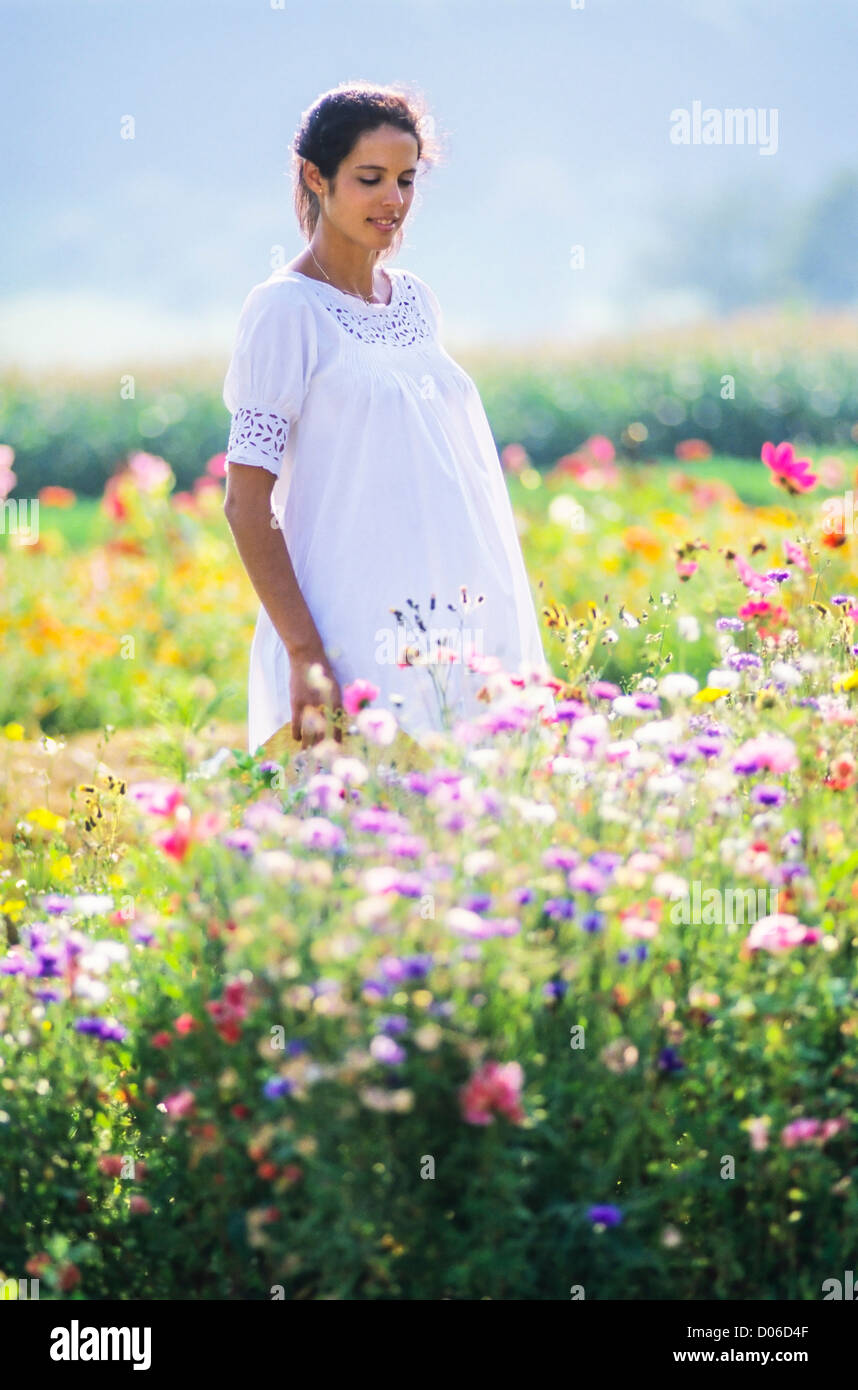 Femme enceinte debout dans le jardin de fleurs Banque D'Images