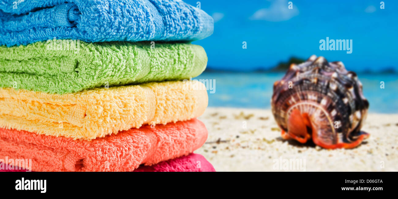 Serviettes colorées sur une plage de sable blanc avec une magnifique sea shell Banque D'Images