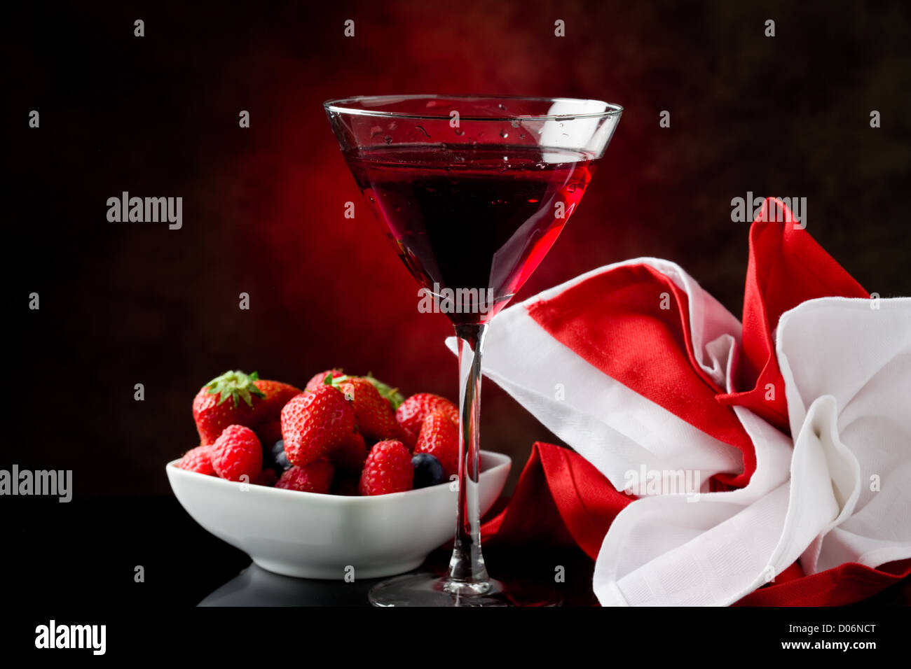 Photo de calice avec cocktail aux fruits rouges sur fond rouge Banque D'Images