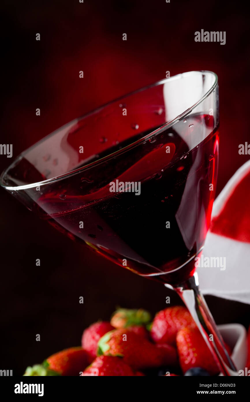 Photo de calice avec cocktail aux fruits rouges sur fond rouge Banque D'Images