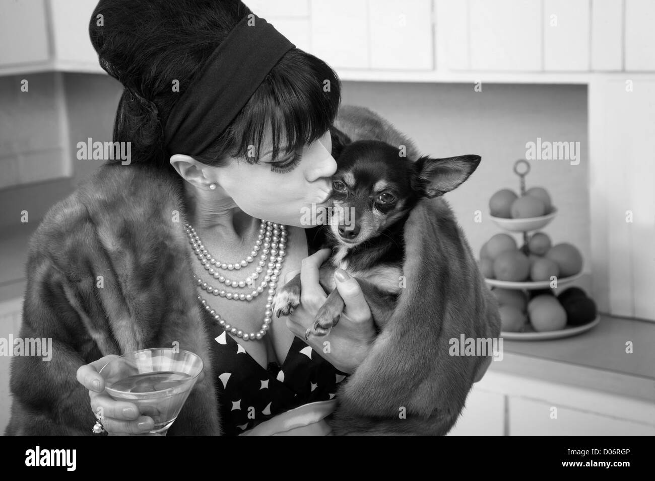 Middled-aged woman en manteau de fourrure avec un chien chihuahua baisers martini Banque D'Images