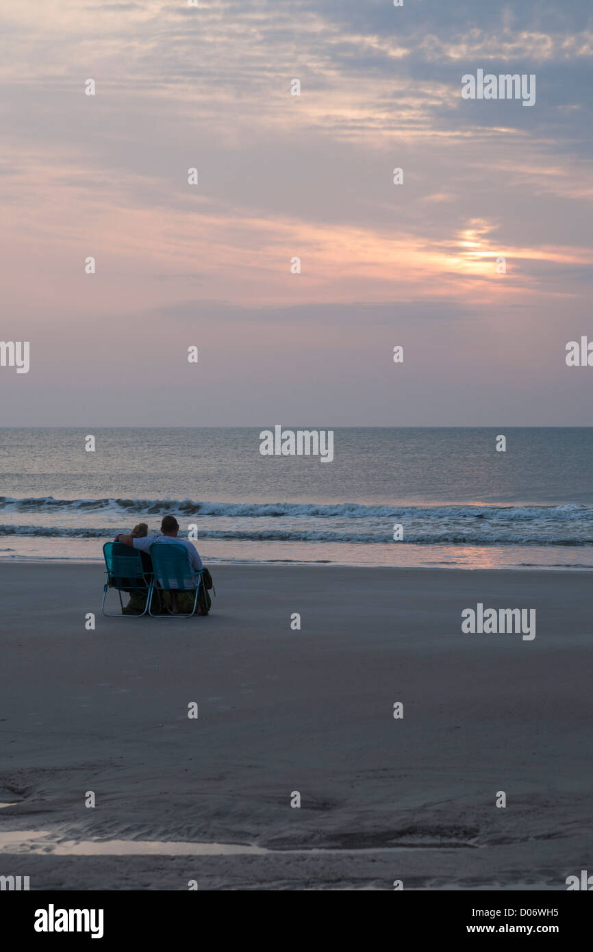 Couple s'asseoir ensemble sur des chaises de plage regardant lever du soleil sur l'océan Atlantique à Amelia Island, Floride Banque D'Images