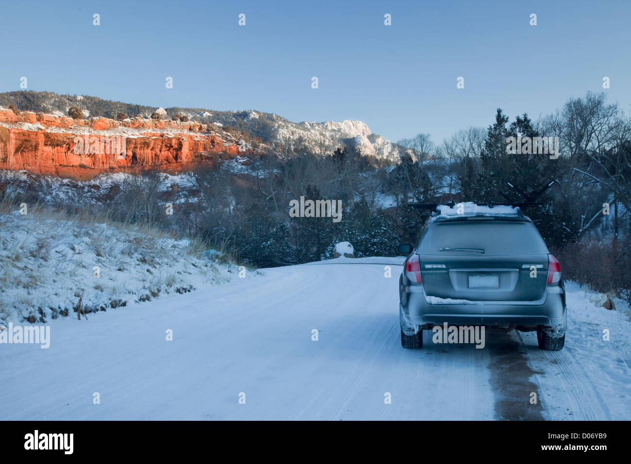 Voiture de tourisme et route couverte de neige dans l'arrière-pays du Colorado avec ses falaises de grès rouge Banque D'Images