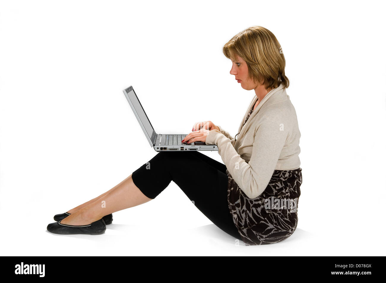 Une jeune femme assise sur le sol et de travailler sur son ordinateur portable Banque D'Images
