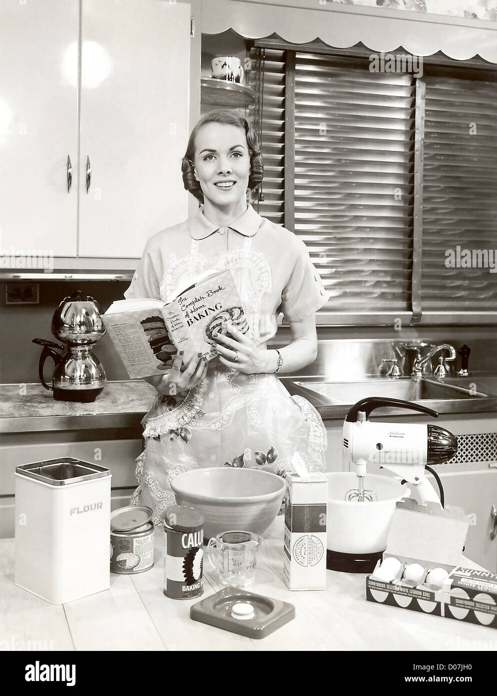 Woman with apron holding cookbook Banque D'Images