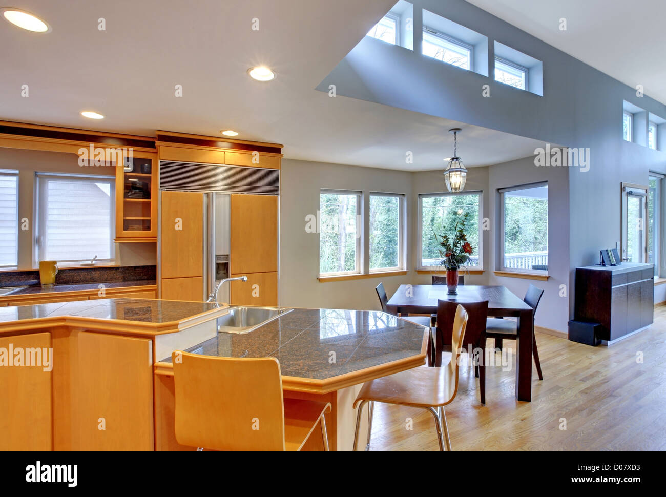 Grande cuisine en bois moderne de luxe avec des plans de travail en granit et plancher de bois jaune. Banque D'Images