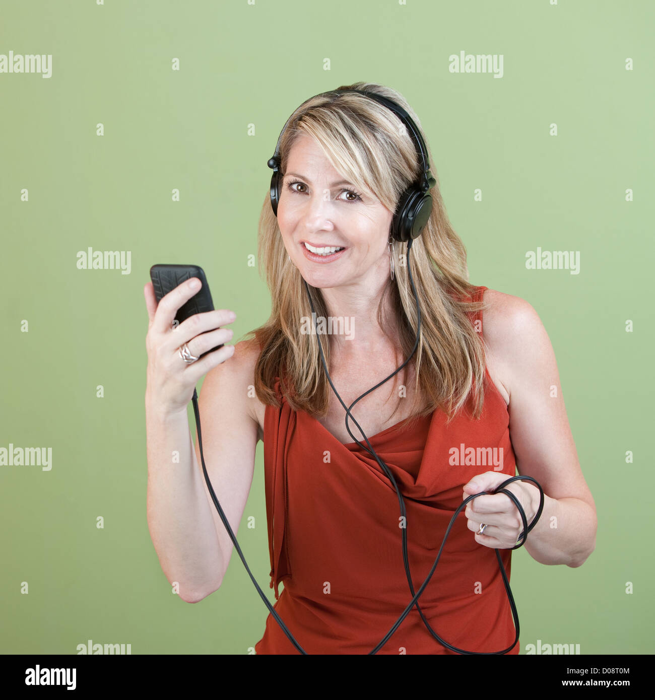 Femme d'âge moyen à l'écoute de music player sur fond vert Banque D'Images