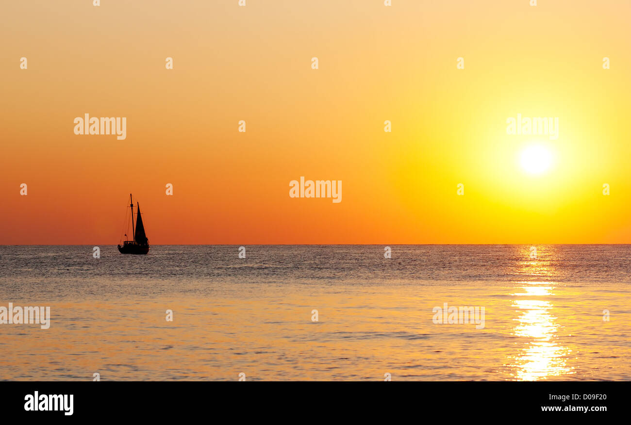 Coucher du soleil doré sur une mer avec silhouette d'un yacht. Banque D'Images