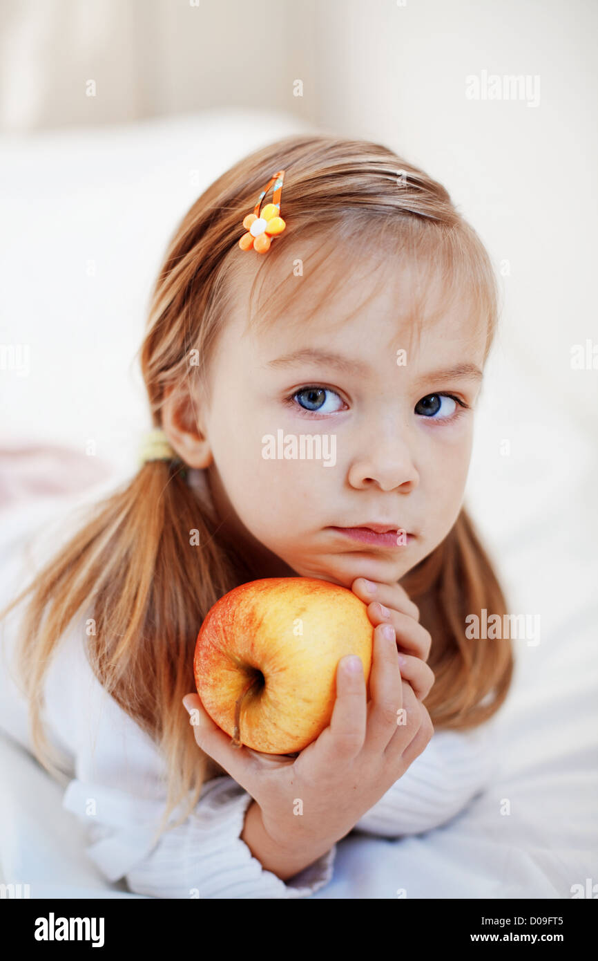 De l'enfant mignon occasionnel avec apple au lit Banque D'Images