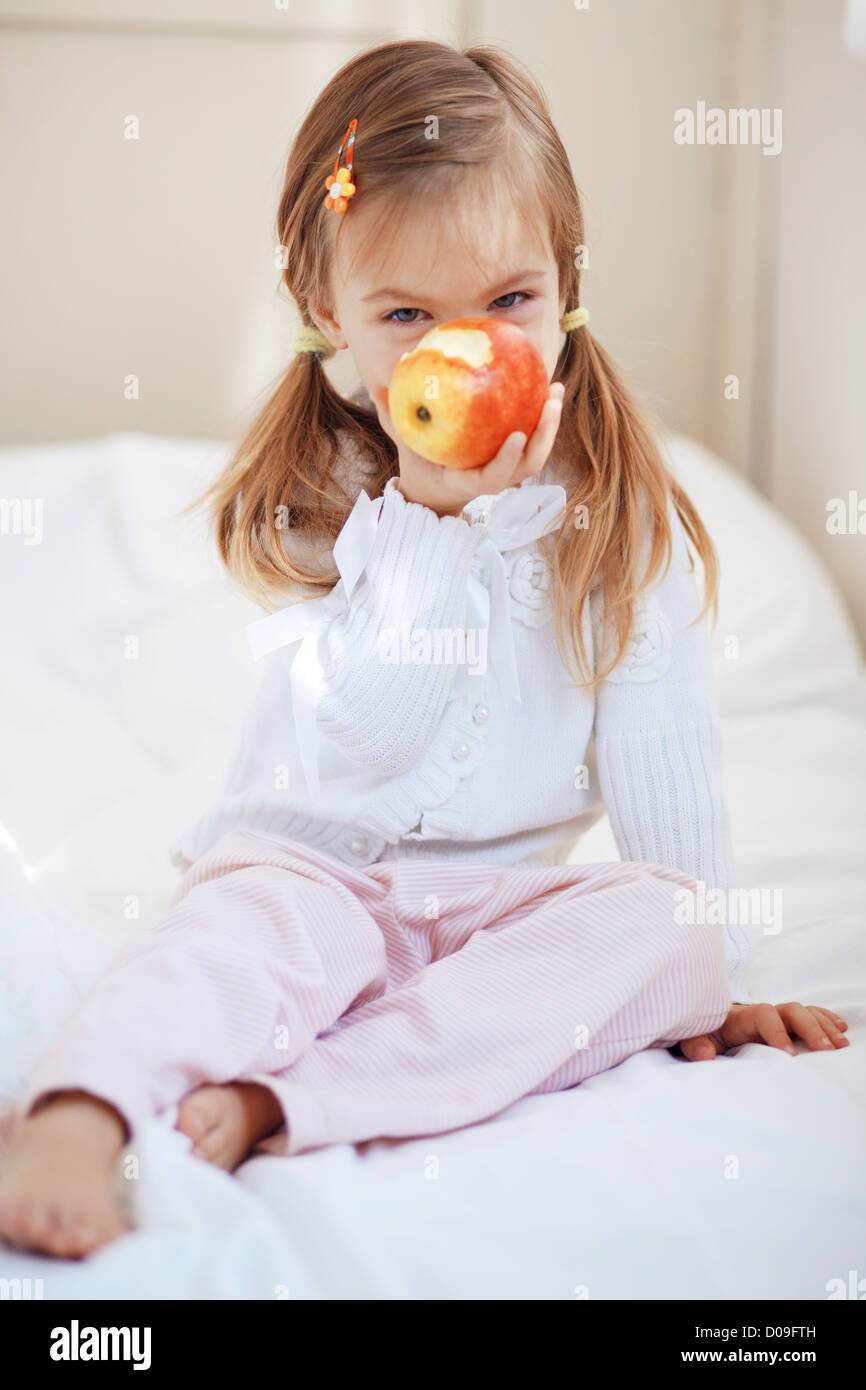 De l'enfant mignon occasionnel avec apple au lit Banque D'Images