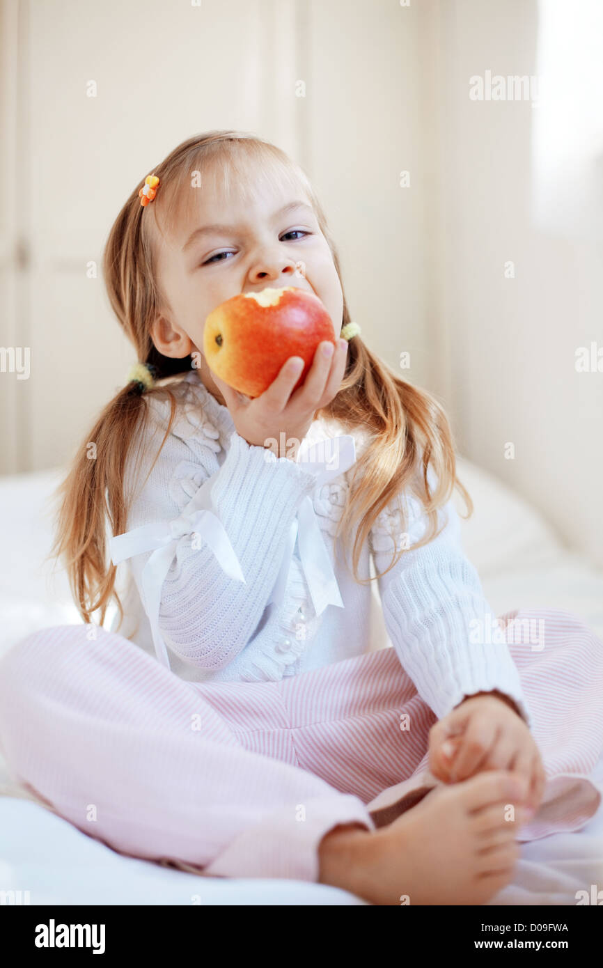 De l'enfant mignon occasionnel avec apple au lit Banque D'Images