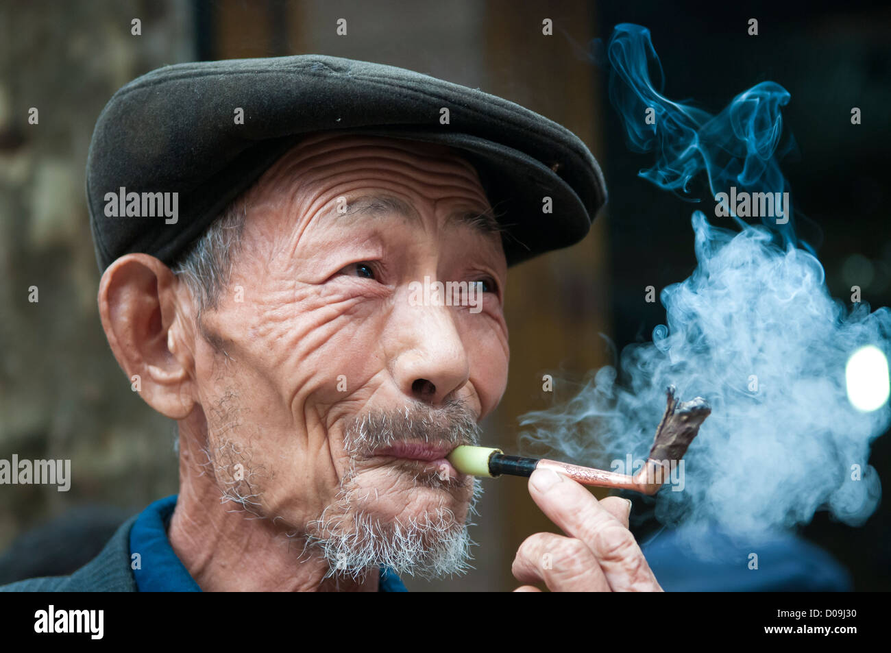 L'homme fume pipe tout en discutant avec des amis le jour du marché dans le village à la périphérie de Chengdu, province du Sichuan, Chine Banque D'Images