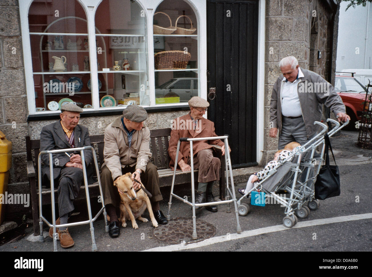 Grand-père avec grand enfant visiter de vieux hommes zimmer frames assis sur un banc à l'avant du shop Banque D'Images
