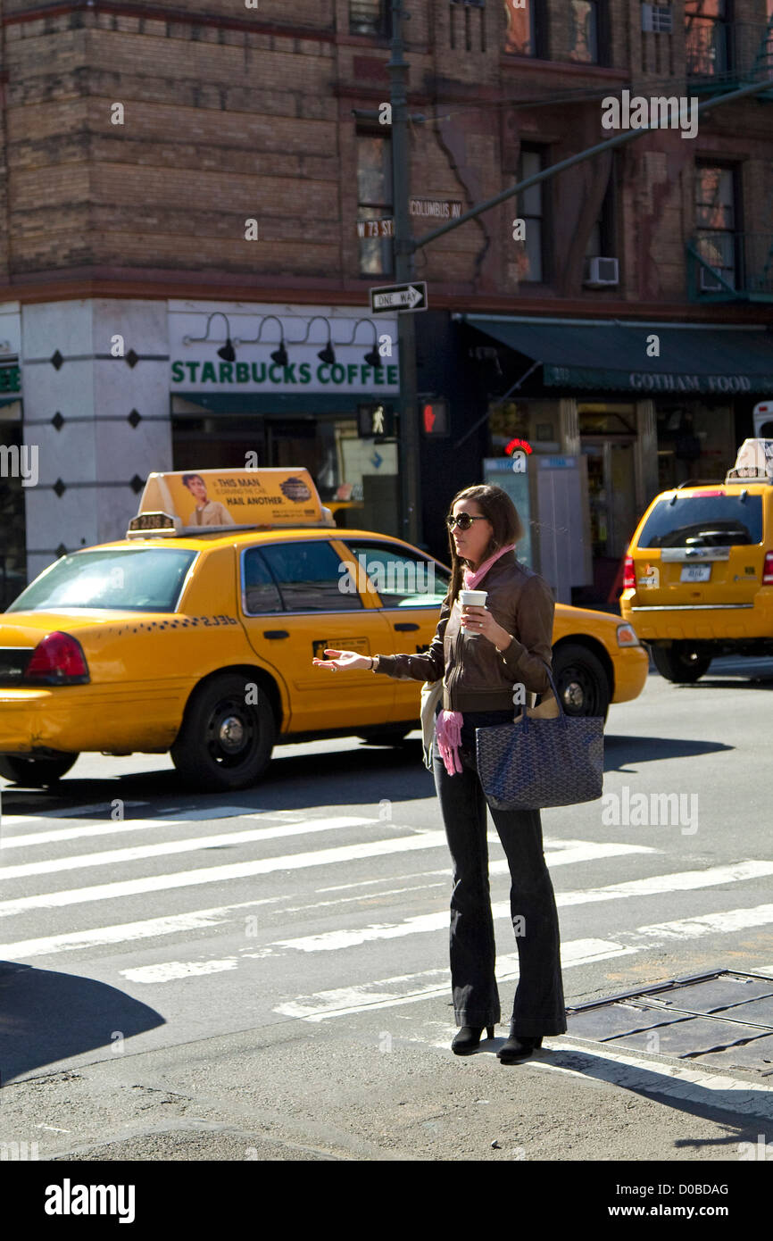 Woman hailing taxi cab sur New York City Street corner, Upper West Side, quartier en face de Starbucks Banque D'Images