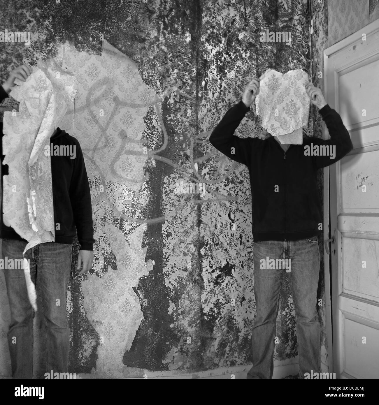 Deux figures masquées par le papier peint déchiré shred dans immeuble abandonné de l'intérieur. Banque D'Images