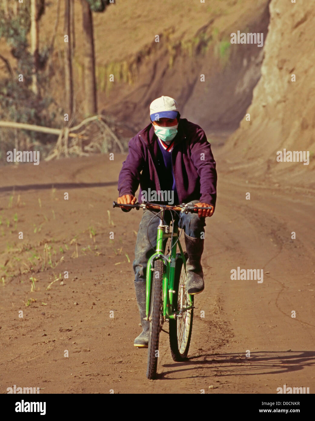 Un cycliste porte un masque pour protéger ses poumons de poussière volcanique Banque D'Images