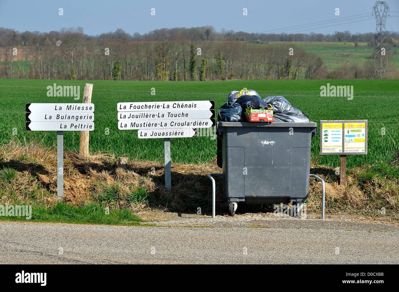 Paysage de la campagne du nord Mayenne. Conteneur à déchets, des panneaux indiquant les noms des fermes, au nord Mayenne (France). Banque D'Images