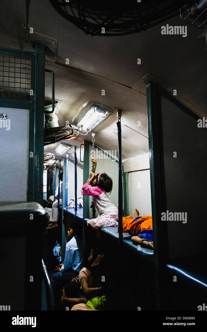 Indian girl assis sur une couchette supérieure à l'intérieur d'un train-couchettes de 2ème classe. Banque D'Images