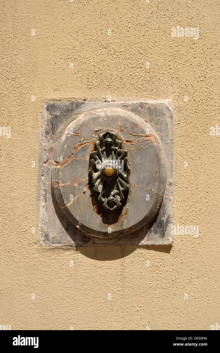 Vieille porte bell situé dans une plaque de marbre à côté d'une porte à Lucques Toscane Italie Banque D'Images