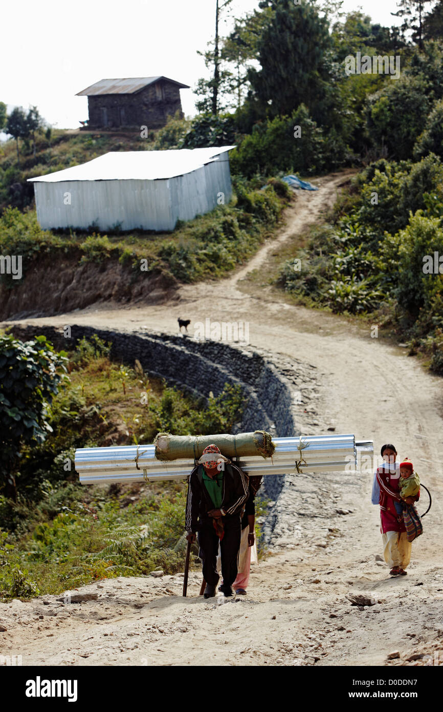 Un homme et femme transporter les fournitures de construction d'un chemin de terre. Banque D'Images