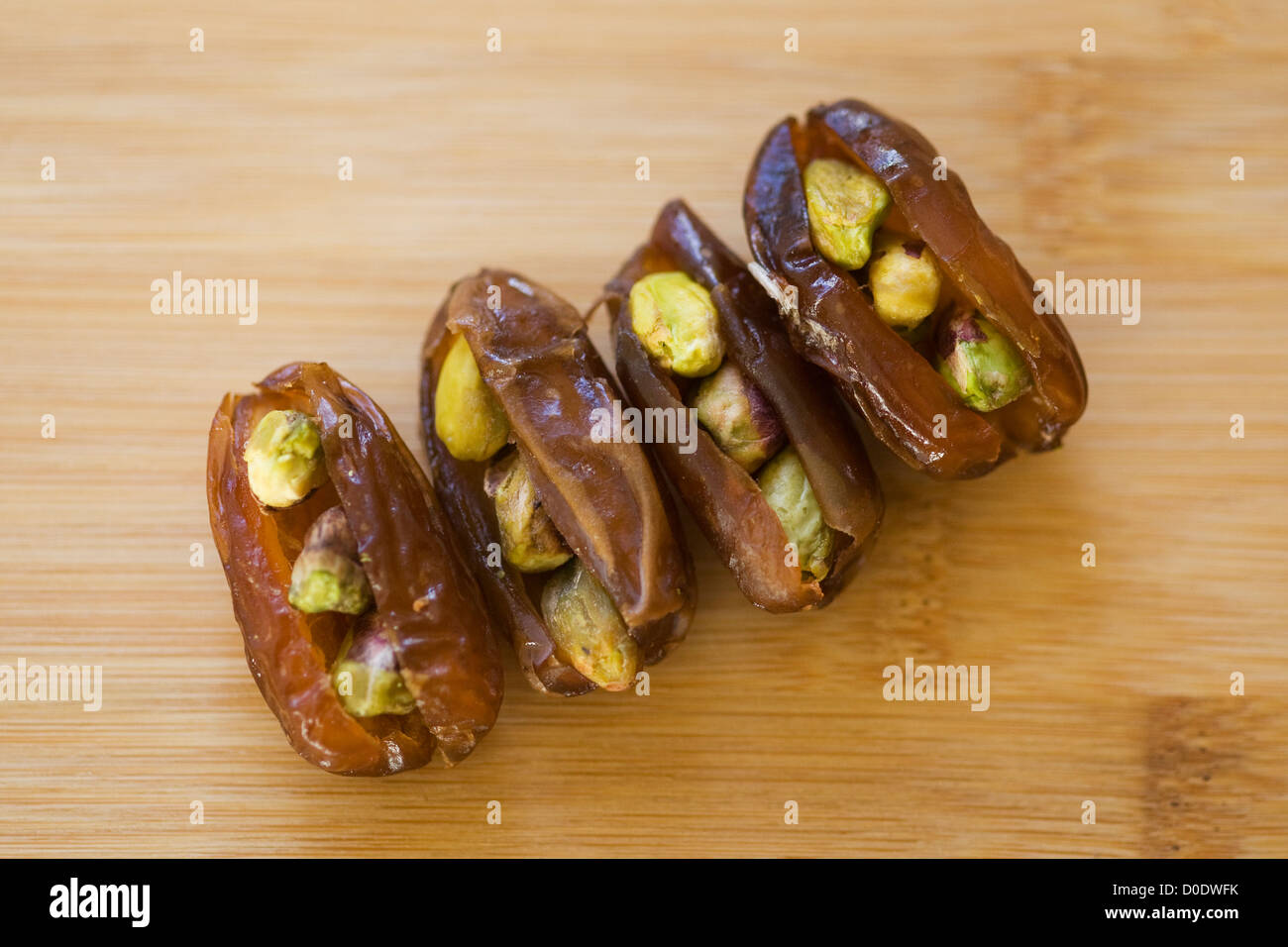 Dates fraîches farcies aux pistaches sur une planche à découper en bambou Banque D'Images