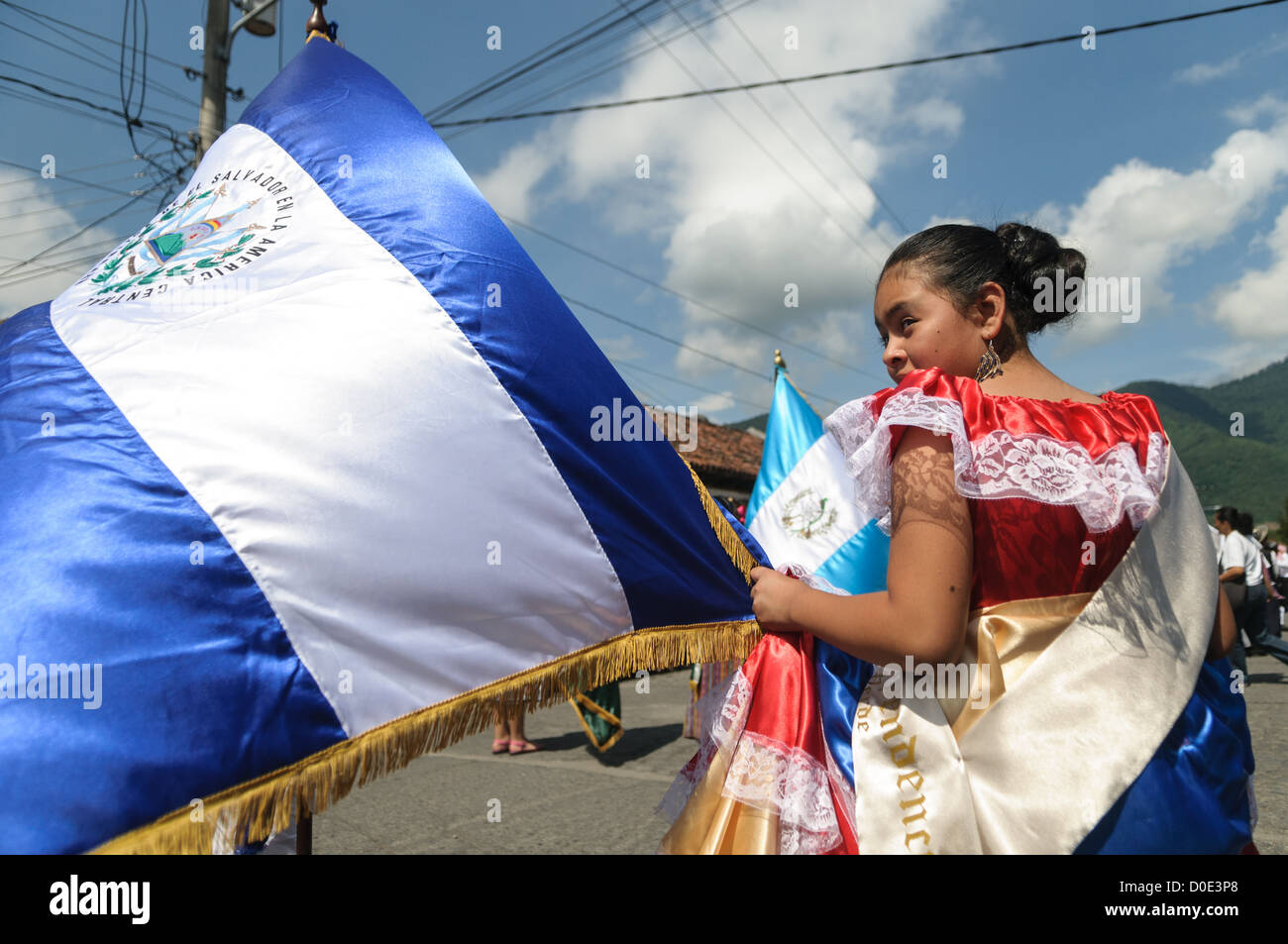 Défilé des écoliers El Salvador drapeau fille tenue traditionnelle Antigua Guatemala // ANTIGUA GUATEMALA, Guatemala — dans la matinée de la veille de la fête de l'indépendance du Guatemala (célébrée le 15 septembre), des centaines d'écoliers d'Antigua et des villages environnants défilent dans un défilé de groupes scolaires à Antigua, certains en costume et d'autres en uniforme scolaire. Le défilé comprend également des orchestres de marche de l'école et des cheerleaders. Le cortège commence au Parque Central et passe devant l'église jaune vif de la Merced et sur le stade municipal. Banque D'Images