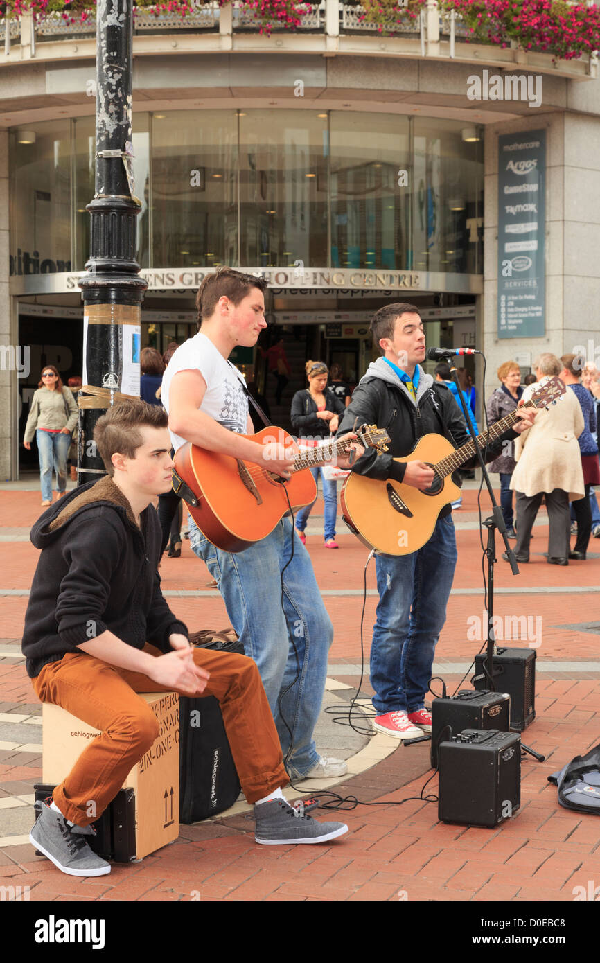 Scène de rue typique avec trois musiciens irlandais jeunes hommes jouant des guitares en bus dans le centre-ville sur Grafton Street Dublin Eire Irlande Banque D'Images