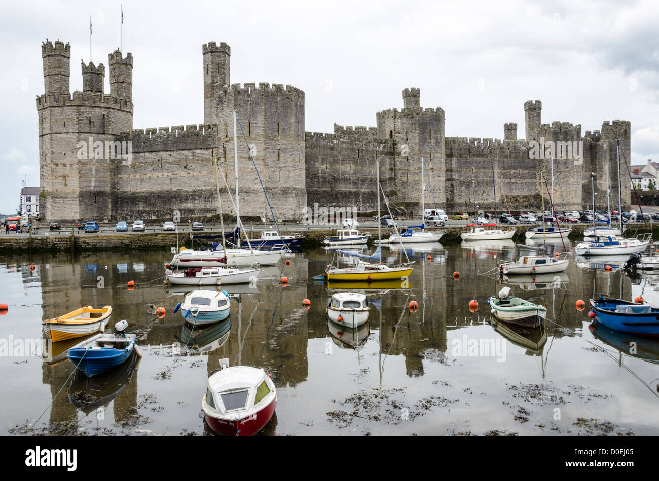 CAERNARFON, Pays de Galles - une vue sur le château de l'autre côté de la rivière, avec des bateaux amarrés dans l'avant-plan, au château de Caernarfon, dans le nord-ouest du pays de Galles. Un château s'élevait à l'origine sur le site remontant à la fin du xie siècle, mais à la fin du 13e siècle, le Roi Edward J'ai commandé une nouvelle structure qui se tient à ce jour. Il possède des tours et est l'un des mieux conservés de la série de châteaux-QUE J'ai commandé. Banque D'Images